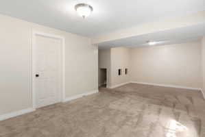 Spacious room featuring neutral carpeting, light-toned walls, and white trim
