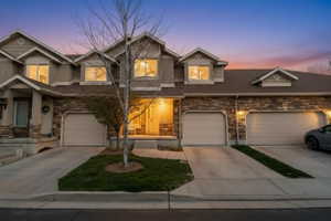 View of front of home featuring stone siding, driveway, and a garage