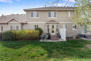 Rear view of house featuring a patio area, a lawn, entry steps, and stucco siding