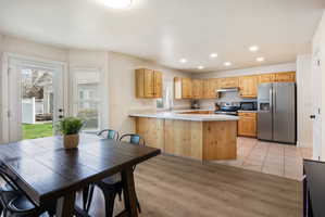 Kitchen featuring light countertops, stainless steel appliances, a peninsula, light wood finish cabinets, and recessed lighting