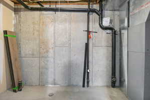 Concrete foundation walls featuring overhead piping and a utility unit