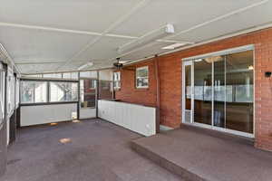 Enclosed sunroom with ceiling fan and stair access to the basement