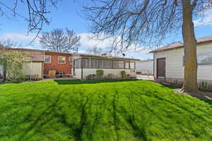 Rear view of house featuring a sunroom, detached garage and storage sheds