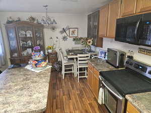 Kitchen featuring stainless steel electric range, black microwave, wood finish cabinets, dark wood-style floors, and suspended lighting