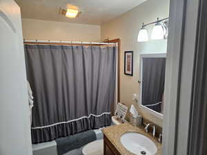 Bathroom with vanity, a textured ceiling, and shower / tub combo