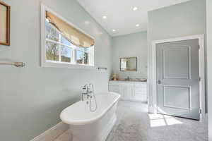 Master bathroom with vanity, a soaking tub, light marble finish flooring, and recessed lighting