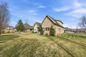 View of property exterior featuring stone siding and a lawn