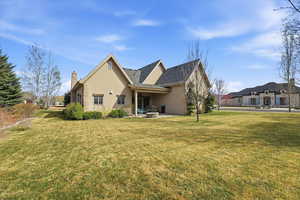 Back of house featuring stucco siding, a lawn, a patio, and a chimney