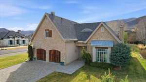 View of front of house with stone and stucco a mountain view, front yard, and garage