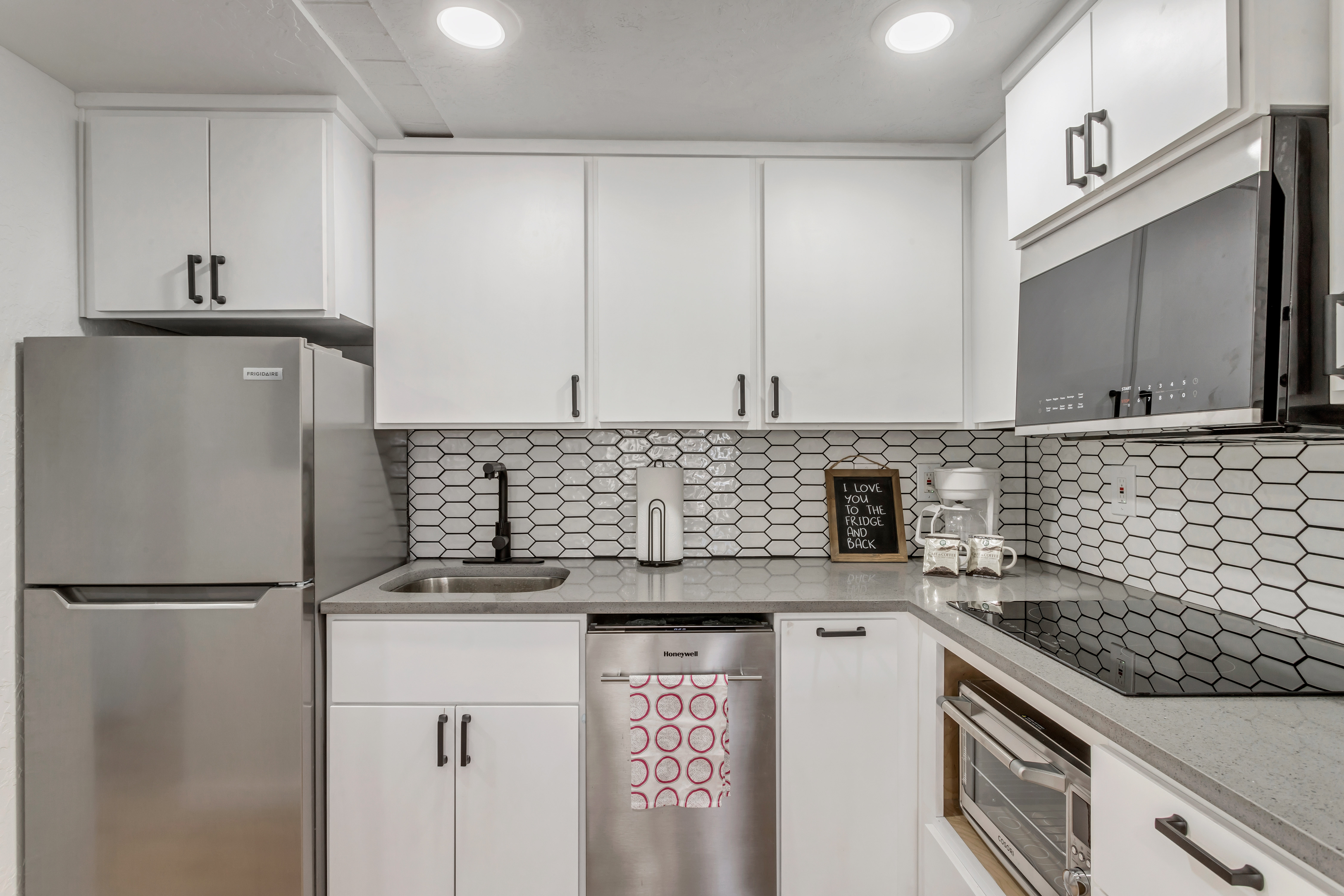 Kitchen featuring white cabinetry, stainless steel appliances, light stone counters, recessed lighting, and tasteful backsplash