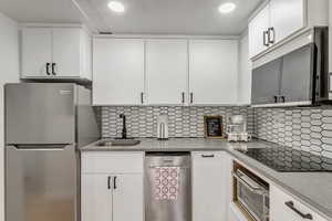 Kitchen featuring white cabinetry, stainless steel appliances, light stone counters, recessed lighting, and tasteful backsplash