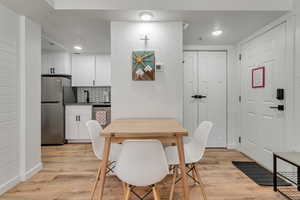 Dining room featuring light wood-type flooring, a textured wall, and recessed lighting
