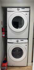 Laundry area with stacked washer / dryer, light wood-style floors, and a textured wall