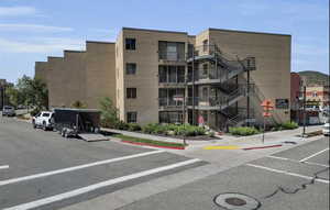 View of apartment building / complex featuring uncovered parking