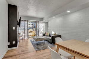 Living room featuring light wood-style flooring, a textured ceiling, and recessed lighting