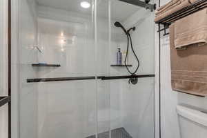 Full bath featuring a shower stall and toilet