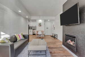 Living room featuring light wood-type flooring, a fireplace, a textured ceiling, and recessed lighting