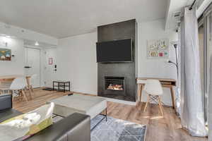 Living area featuring light wood-type flooring, a large fireplace, a textured ceiling, and a desk