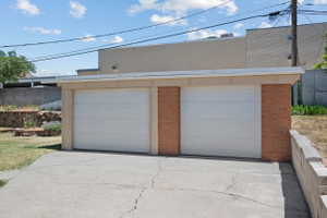 Two-car garage featuring brick accents, white panel doors, and a flat roofline