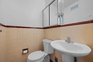 Pedestal sink with chrome faucet, complemented by a medicine cabinet with mirrored sliding doors