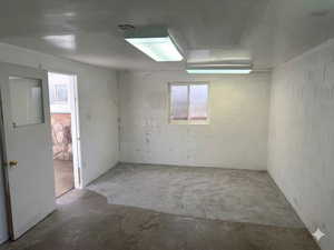 Unfurnished room with unfinished concrete flooring and concrete block wall