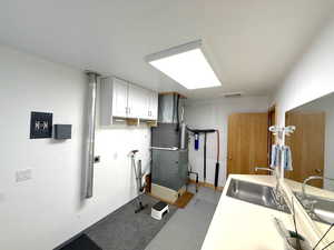 Laundry area with light floors, heating unit, cabinet space, electric dryer hookup, and washer hookup