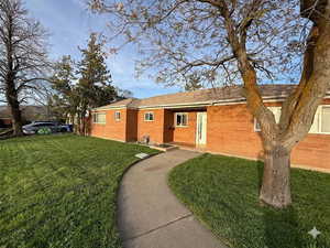 Single story home with a front lawn and brick siding