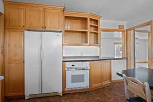 Kitchen featuring light wood cabinetry, built-in oven, dark countertops, and integrated pass-through openings
