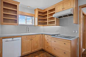 Kitchen featuring light wood cabinetry, light countertops, a white dishwasher, a built-in electric cooktop, and an undermount sink with a gooseneck faucet
