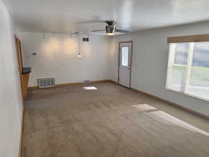 Spare room featuring track lighting, light colored carpet, and a ceiling fan