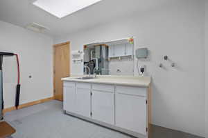 Utility space featuring a built-in sink with a gooseneck faucet, white cabinetry, and a light-toned countertop