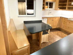 Kitchen featuring light wood finish cabinetry, tasteful backsplash, and white dishwasher