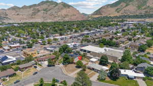 Expansive aerial perspective showcasing the property's location within a developed neighborhood, featuring surrounding commercial buildings, residential structures, and established trees