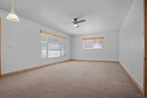 Spacious room featuring neutral carpeting, white walls, and natural wood trim