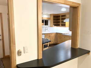 Kitchen featuring light wood finish cabinets, dark countertops, extractor fan, and electric stovetop