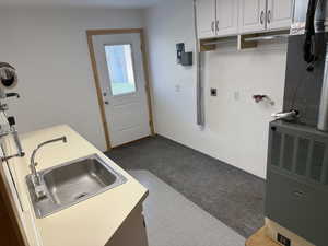 Laundry room featuring heating unit, electric dryer hookup, cabinet space, and washer hookup