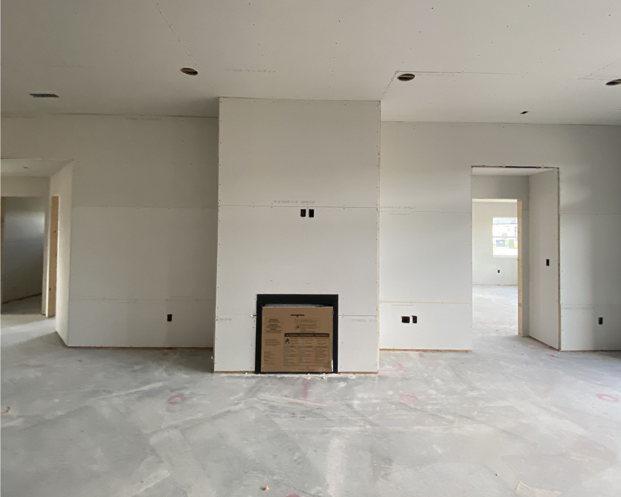 Spacious interior with an unfinished fireplace, recessed lighting, and wall cutouts for future electrical outlets