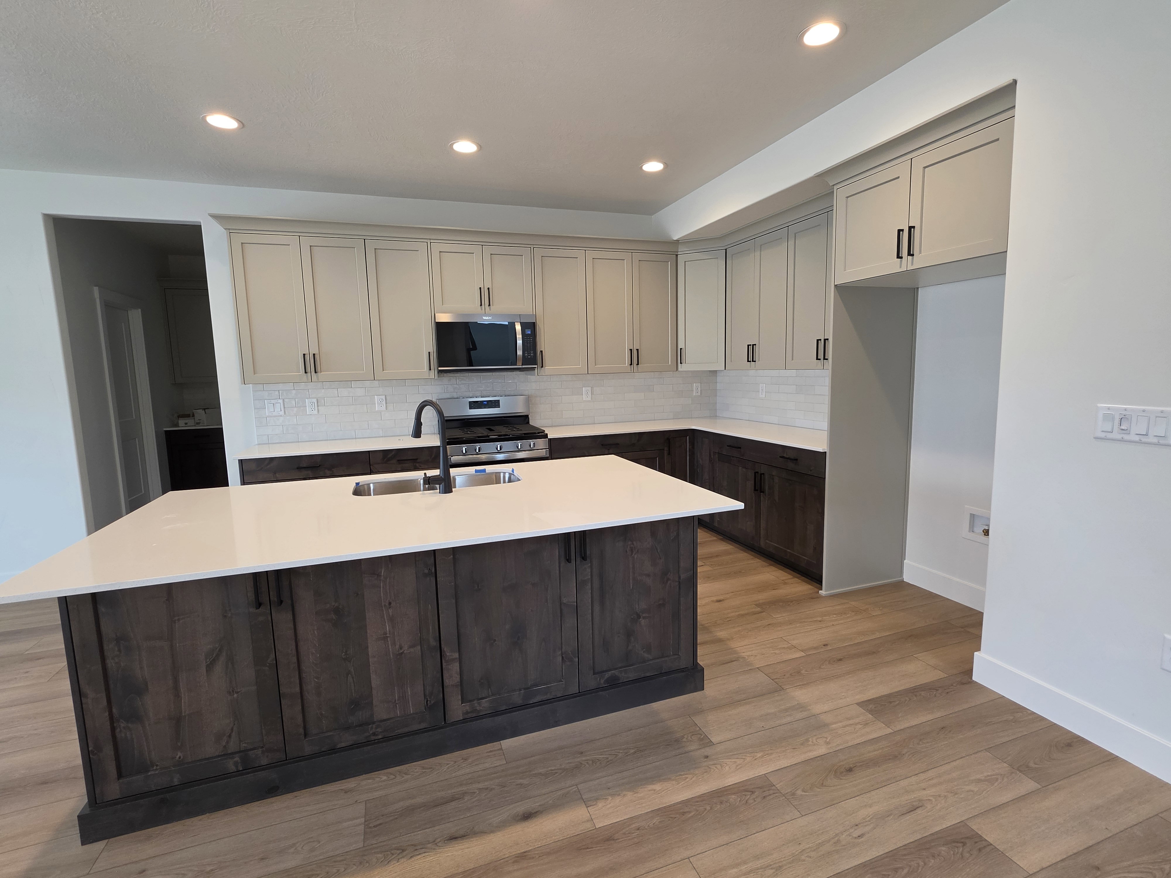 Modern kitchen featuring a large island with a stainless steel undermount sink and a matte black faucet