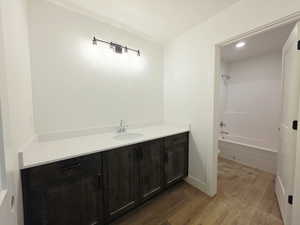 Full bathroom with vanity, light wood-style floors, washtub / shower combination, and recessed lighting