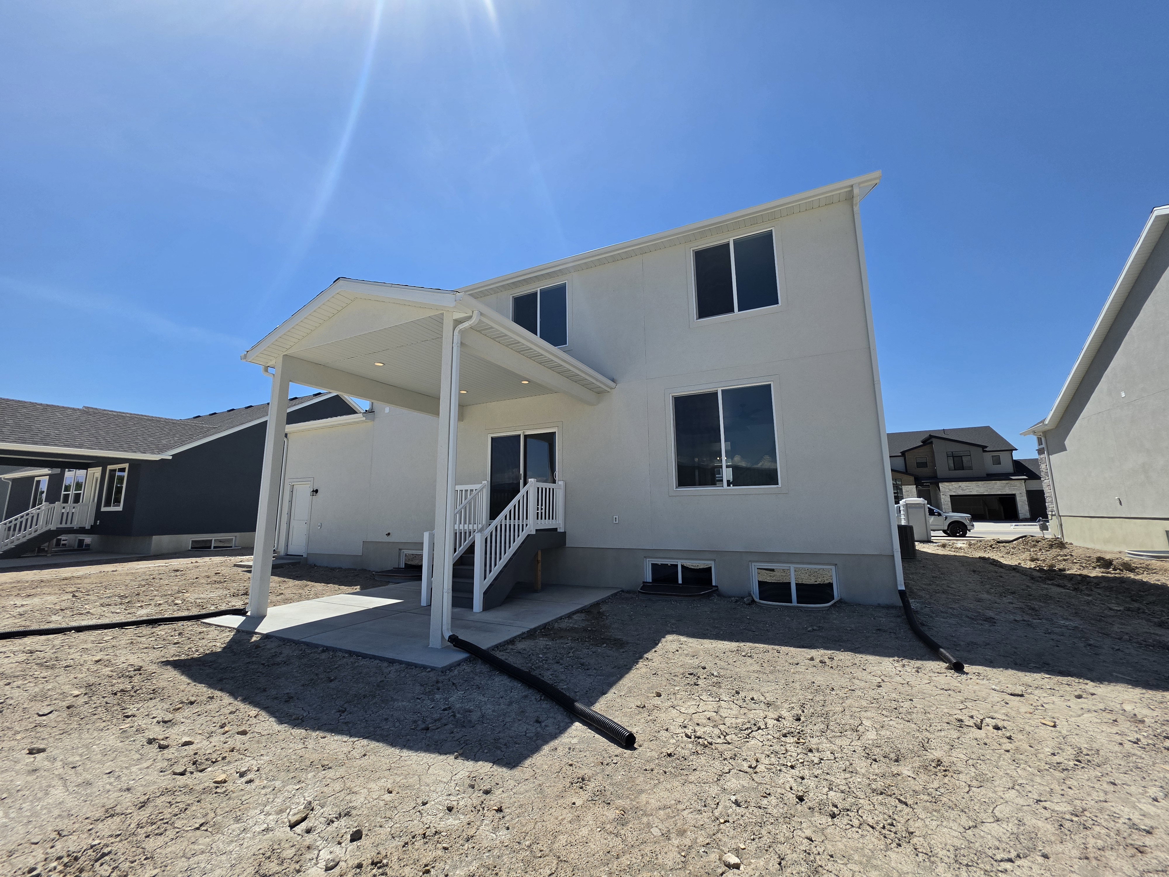 Rear exterior featuring a covered patio, concrete pad, exterior lighting, and a walk-out basement