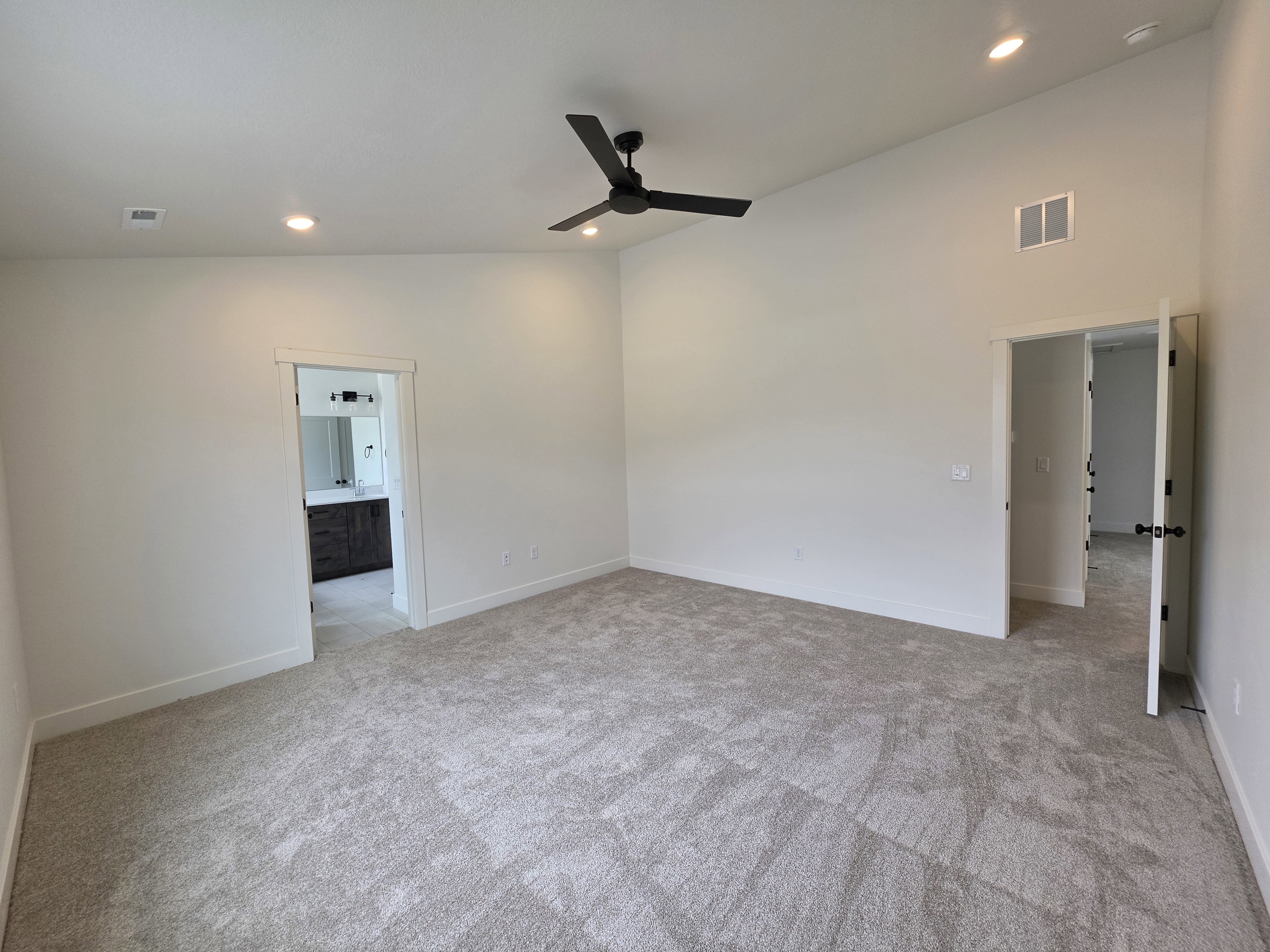 Spacious room featuring vaulted ceilings, light-toned carpeting, recessed lighting, and a contemporary ceiling fan