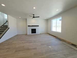 Unfurnished living room with recessed lighting, light wood finished floors, a tile fireplace, ceiling fan, and a textured ceiling