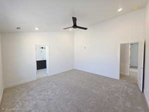 Unfurnished bedroom featuring light carpet, a ceiling fan, recessed lighting, vaulted ceiling, and ensuite bath