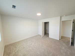 Unfurnished bedroom with light colored carpet and a spacious closet