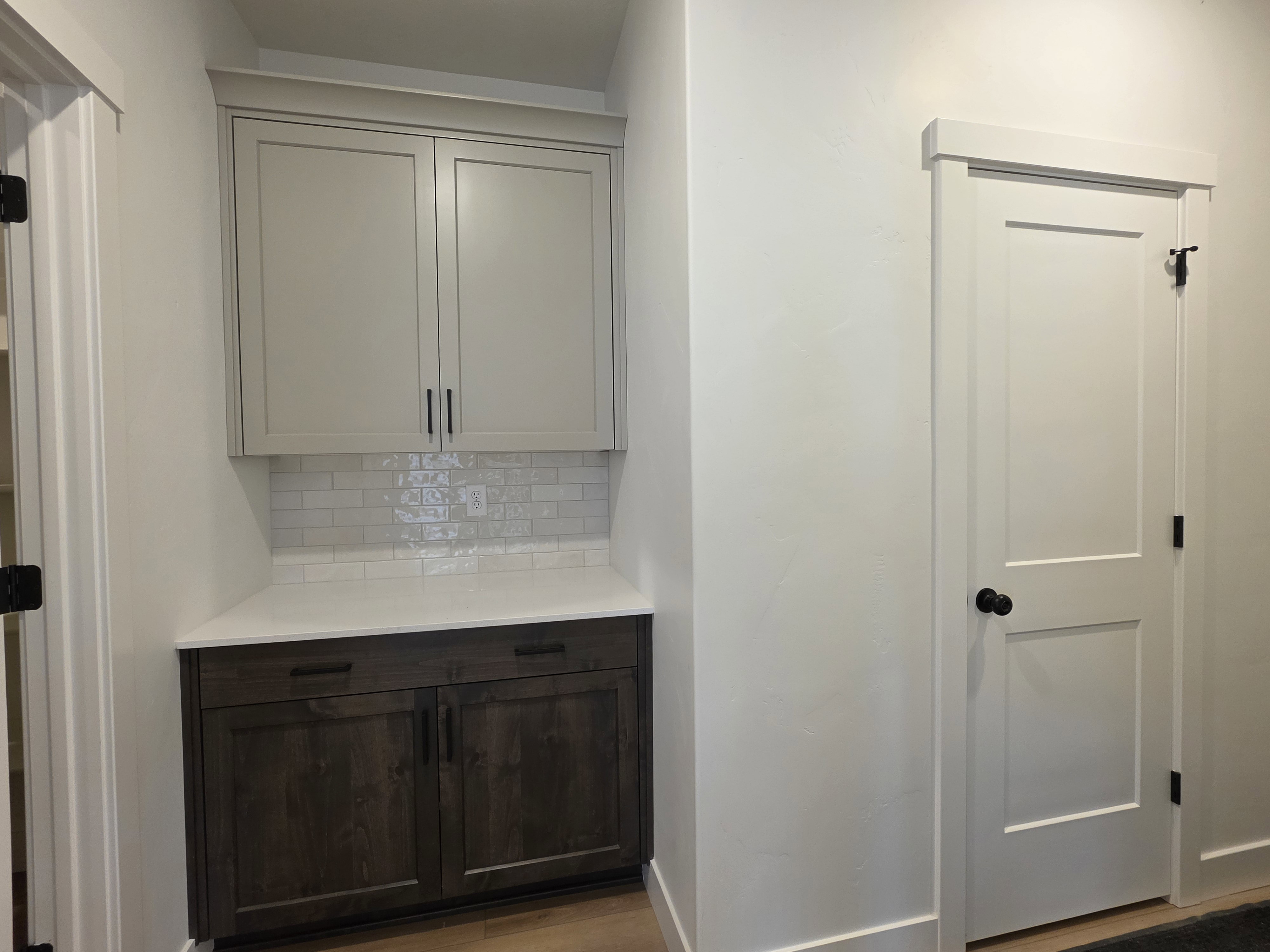 Built-in cabinetry featuring white shaker-style uppers, dark wood-finish lower cabinets, and a white countertop