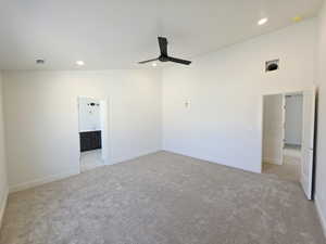 Unfurnished bedroom featuring vaulted ceiling, light colored carpet, a ceiling fan, recessed lighting, and ensuite bath