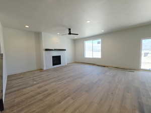 Unfurnished living room featuring recessed lighting, light wood-style flooring, a fireplace, a ceiling fan, and a textured ceiling