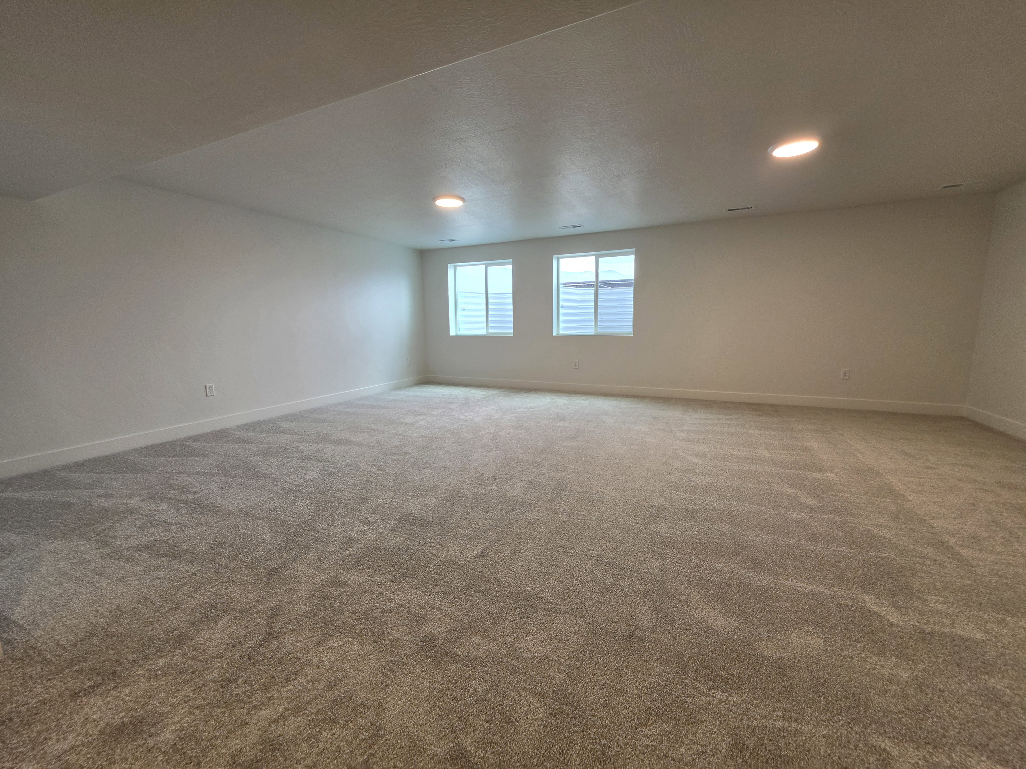 Expansive room featuring plush wall-to-wall carpeting, recessed lighting, and crisp white walls