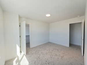 Unfurnished bedroom with light colored carpet and a spacious closet