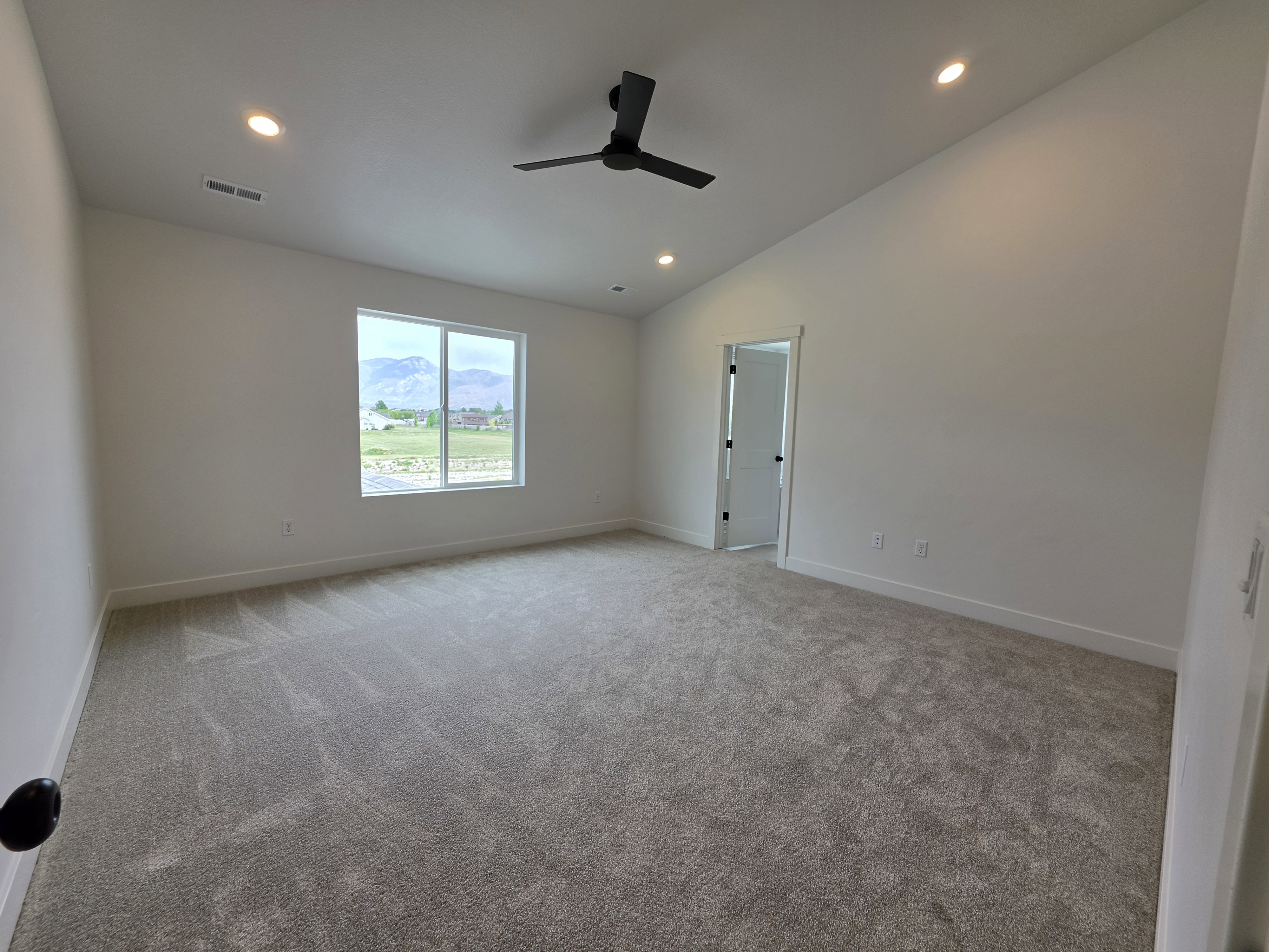Spacious interior with neutral carpeting, recessed lighting, and a modern ceiling fan